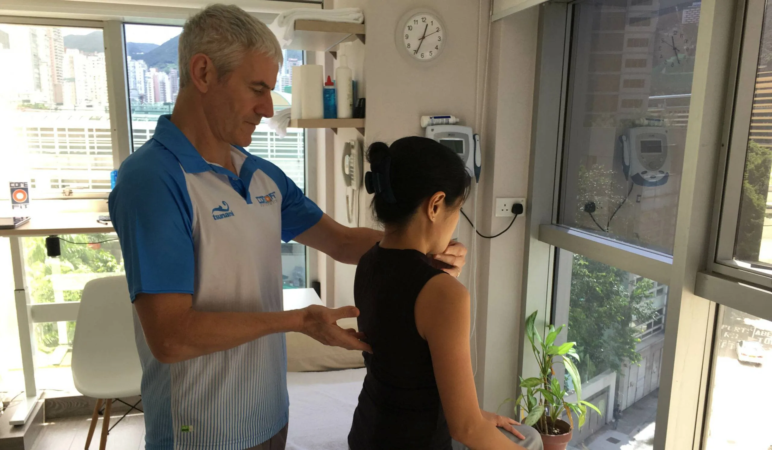 Physical therapist assessing posture of a woman in a clinical setting, focusing on spinal alignment and posture correction.
